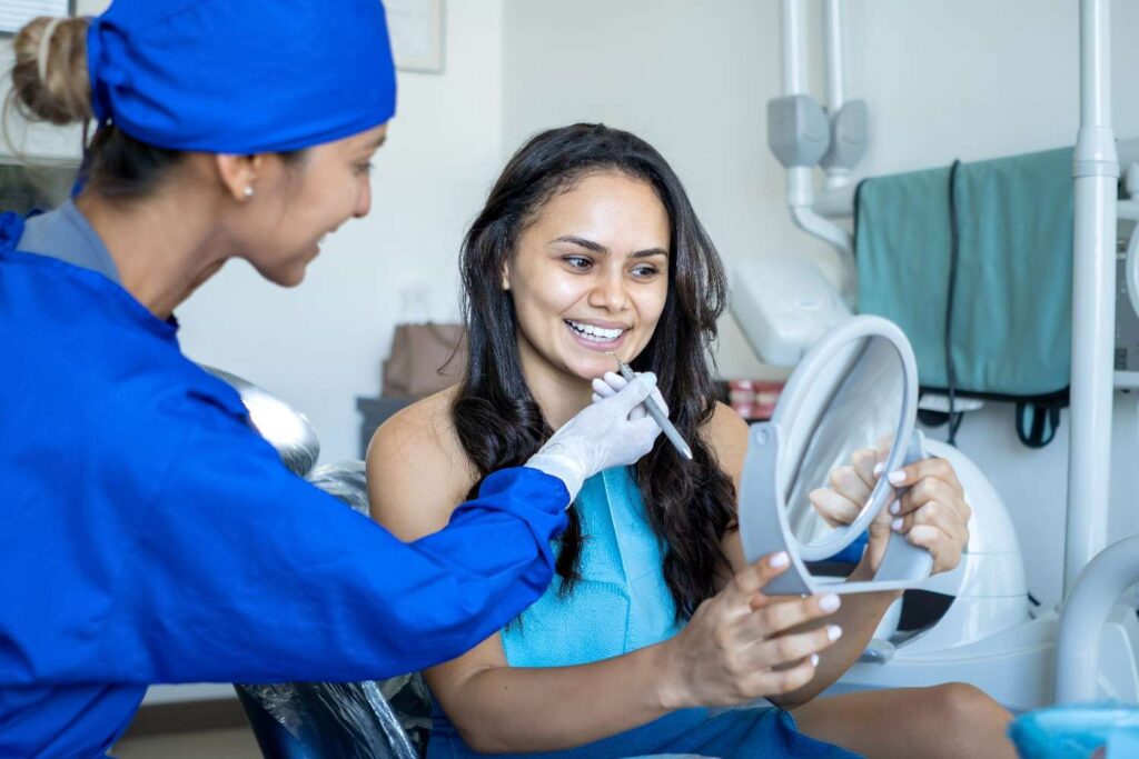 patient-smiles-looks-into-mirror-while-being-seen-by-dentist (2)